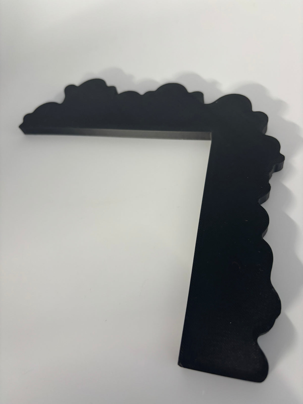 Back view of the black L-shaped ghost door corner decoration on the light surface.