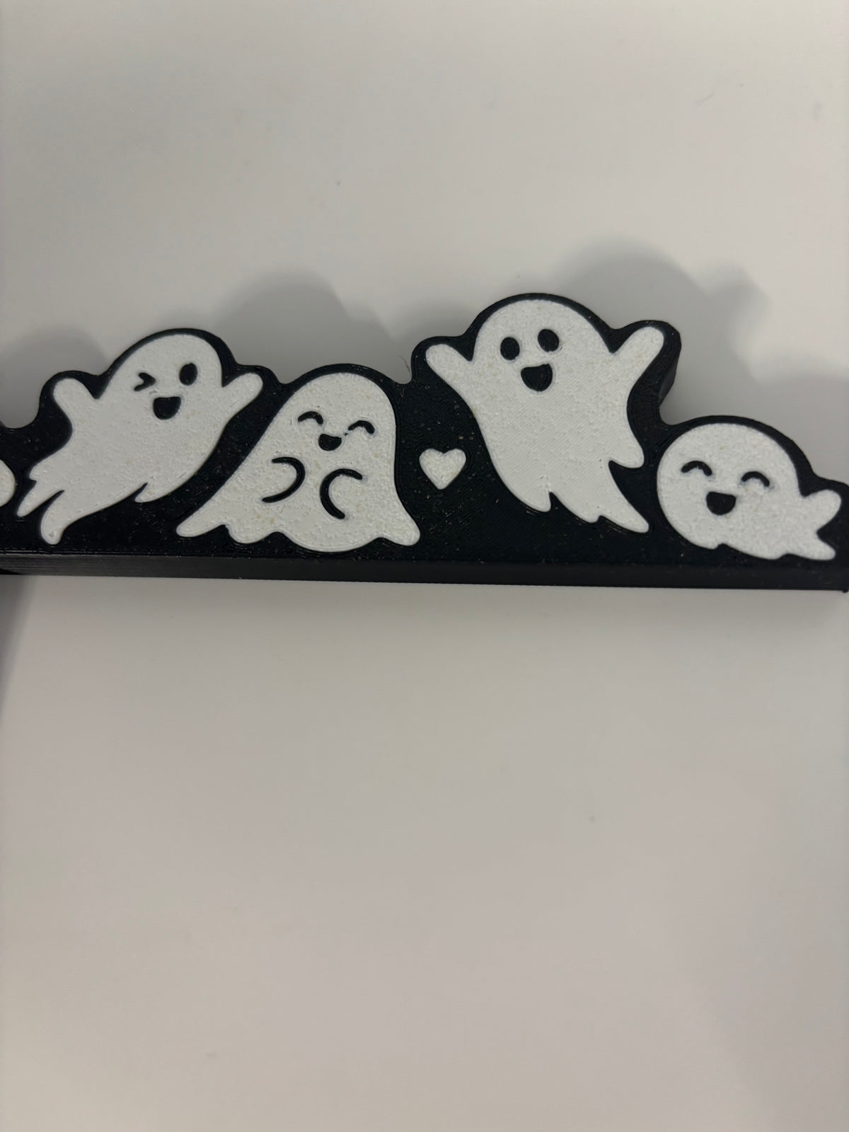 Close-up of white ghost faces along the top of the black door corner decoration.