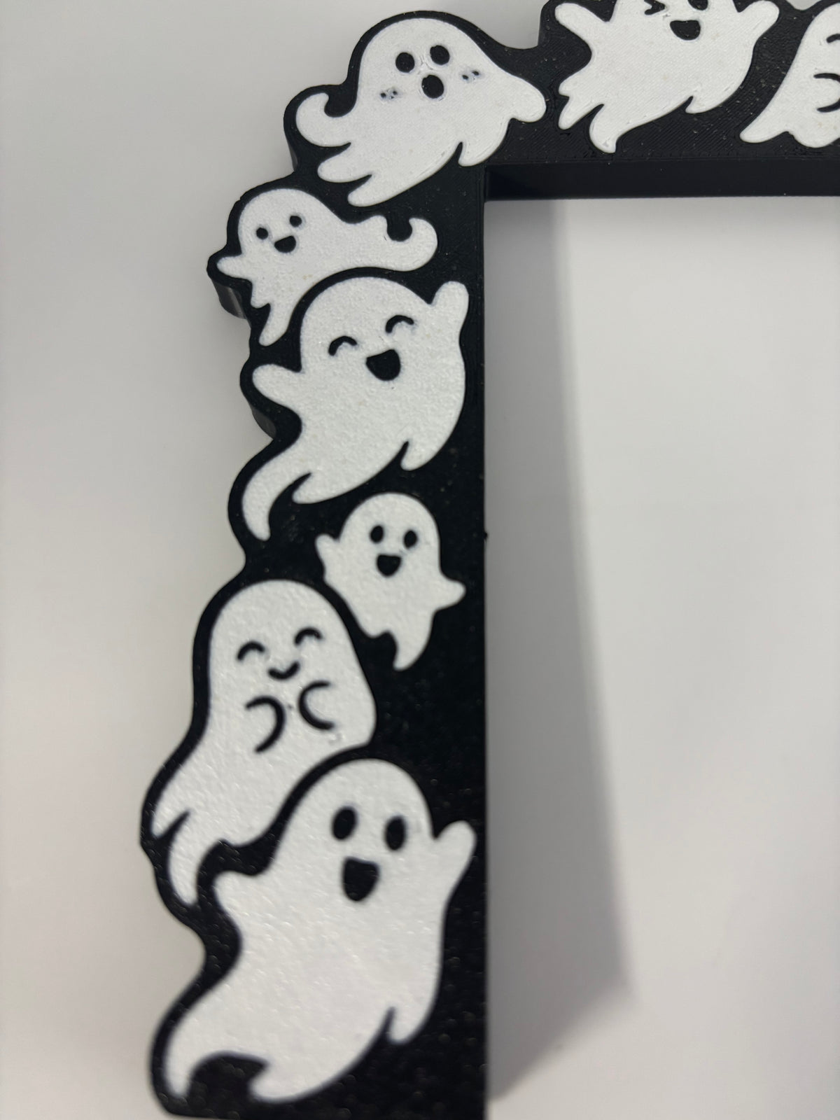 Close-up of white ghost faces along the vertical side of the black door corner decoration.
